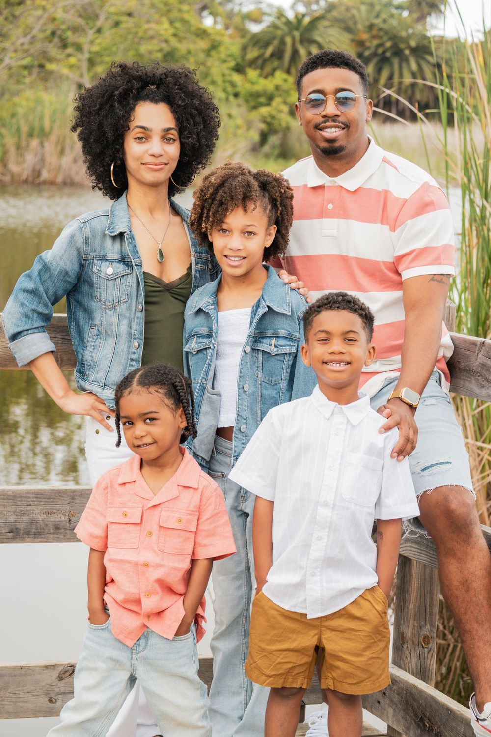 Family portrait session outdoors with coordinated casual outfits in coral, white and denim.