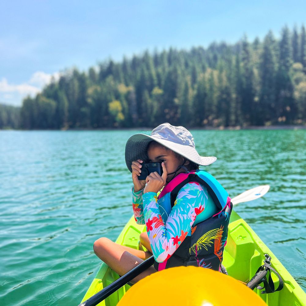 Colorful kayaking adventure on a scenic mountain lake surrounded by evergreen forests.