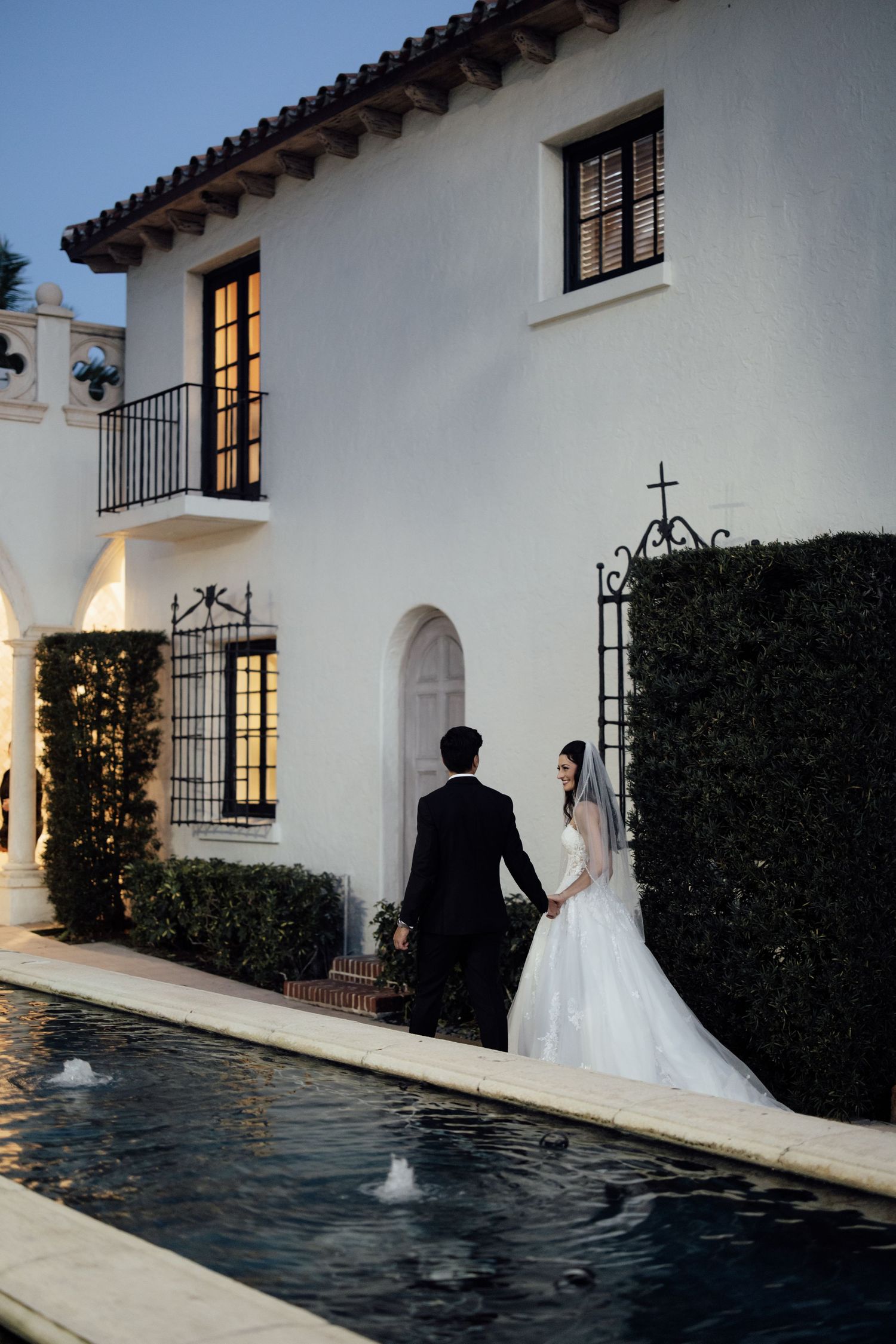 Romantic black and white wedding photo in Palm Beach, Florida with couple embracing on a balcony terrace with palm trees in the background.