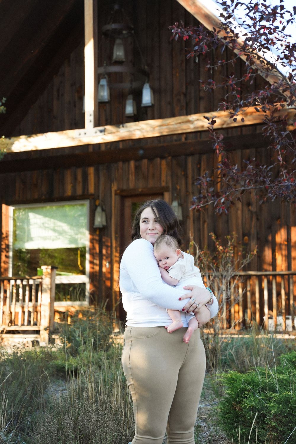 A rustic wooden cabin exterior with greenery and decorative hanging lanterns in the background.