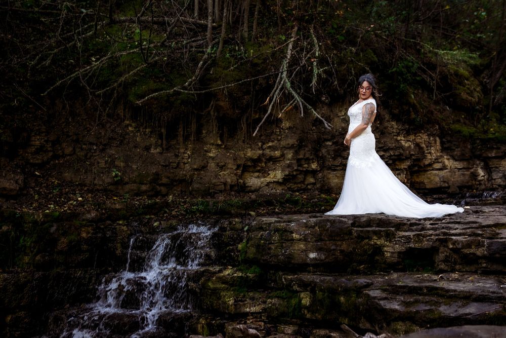 Wedding portraits captured against a scenic waterfall backdrop with dramatic natural lighting.