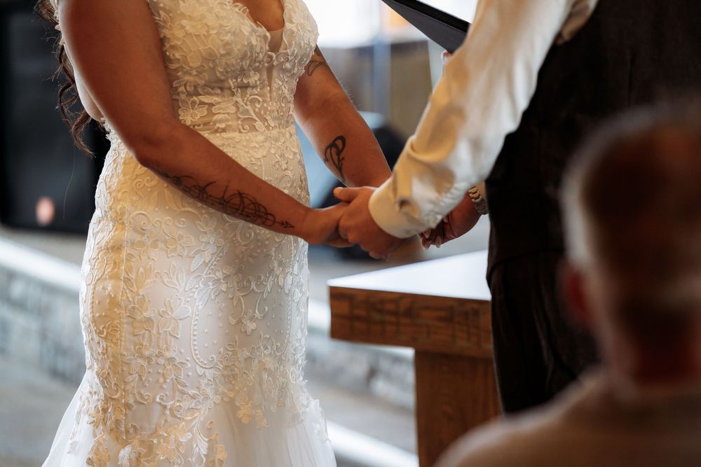 Close-up details of a bride's lace wedding dress being adjusted and buttoned up during wedding preparations.