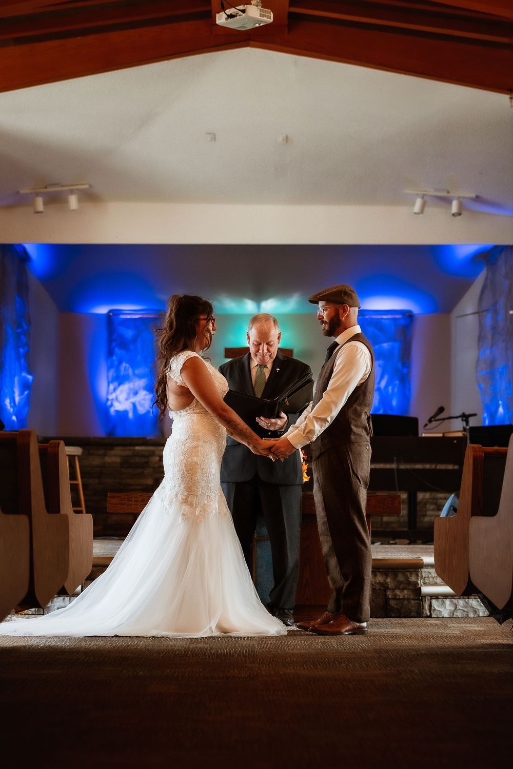 Wedding ceremony moments in a venue with dramatic blue lighting and elegant decor.
