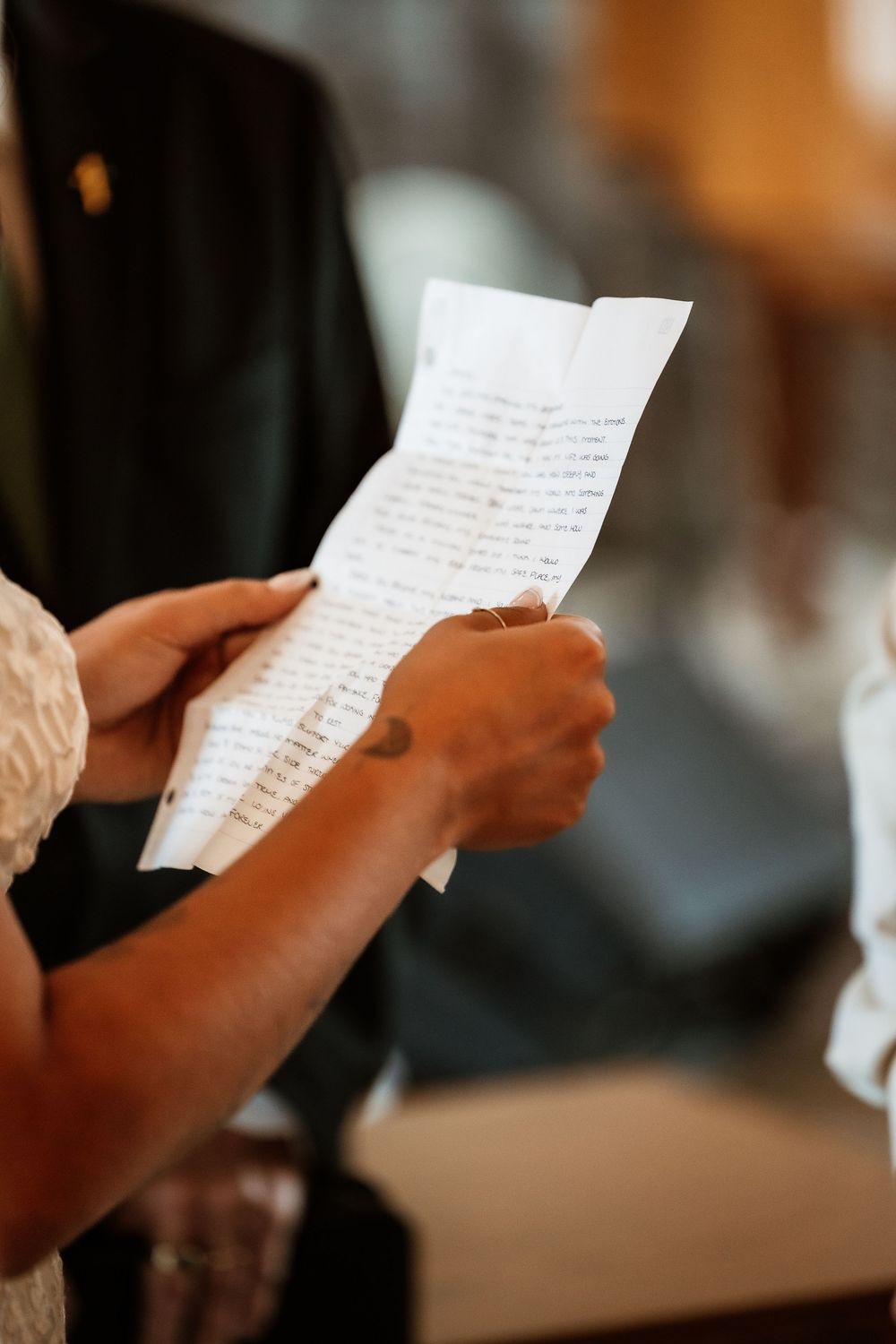 Close-up shot of hands holding handwritten wedding vows on paper.
