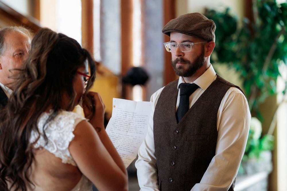 A couple sharing a moment during their wedding ceremony while reading vows indoors.