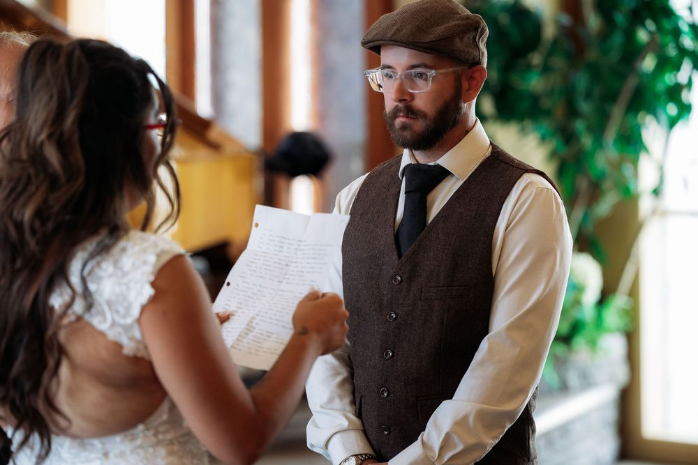 An indoor wedding celebration with guests and couple in rustic attire.