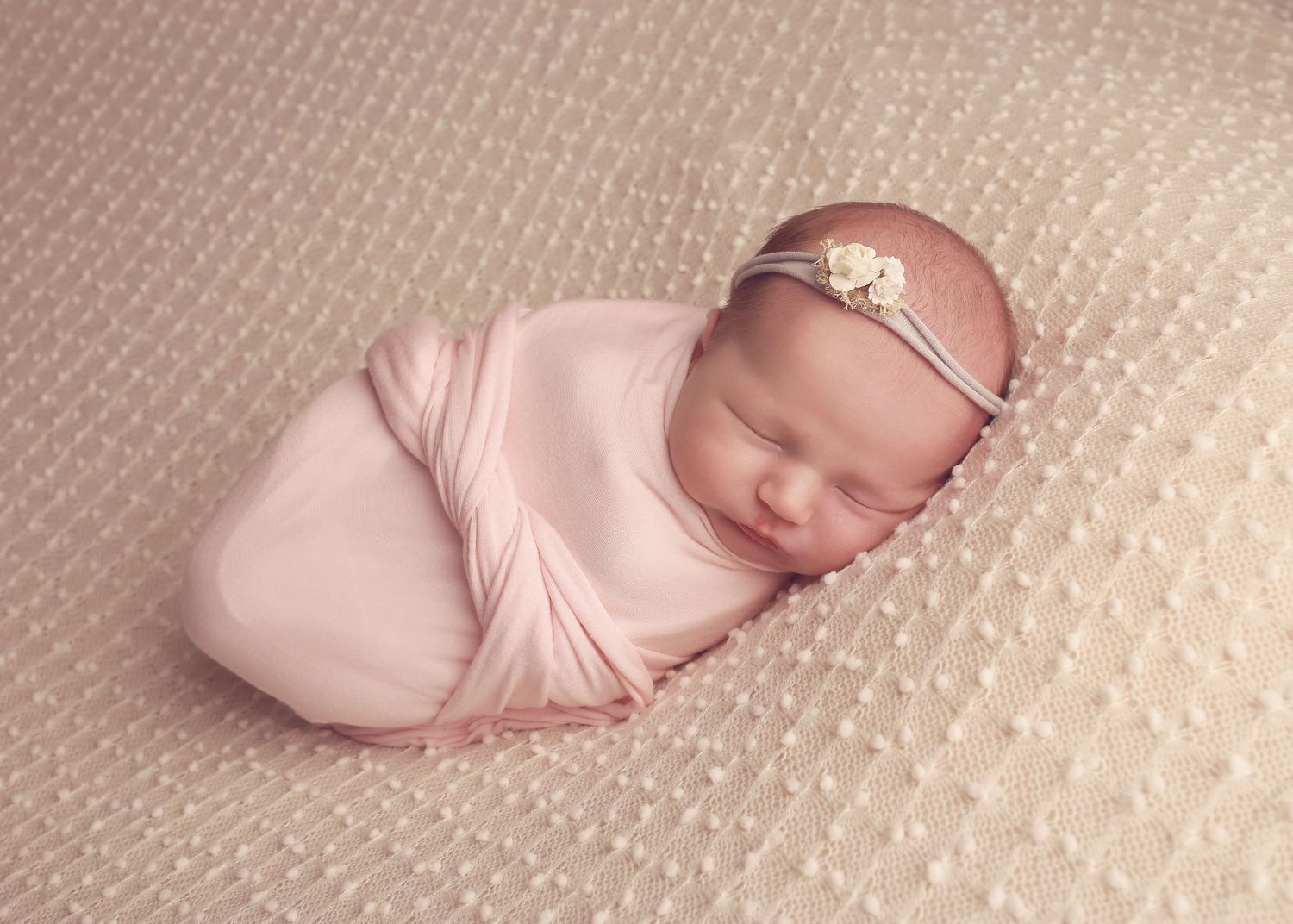 A peaceful newborn baby girl wrapped in soft fabrics, captured in a serene and intimate setting, showcasing the delicate beauty in photo