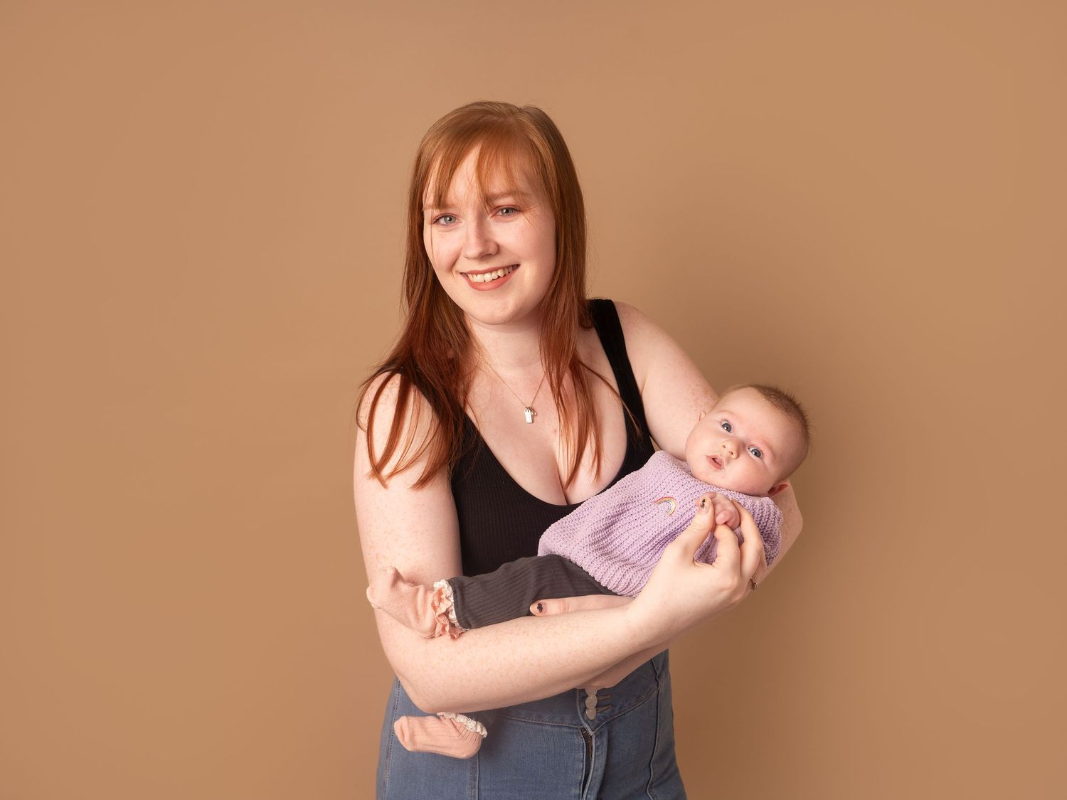 mum holding new baby with knitted purple jumper for newborn family photoshoot in doncaster.