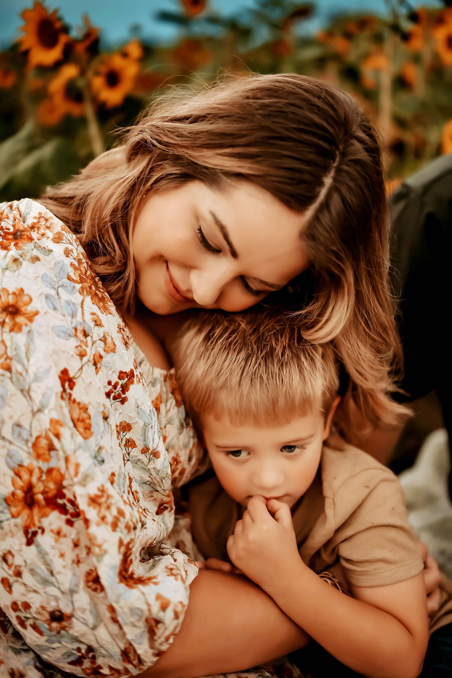A tender embrace shared between parent and child in a sunflower field during golden hour.