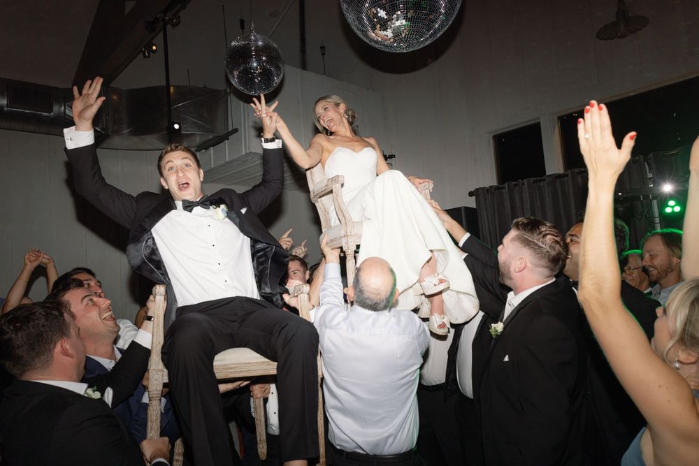 Wedding party celebrations on a dance floor with people being lifted up during a joyous reception moment.