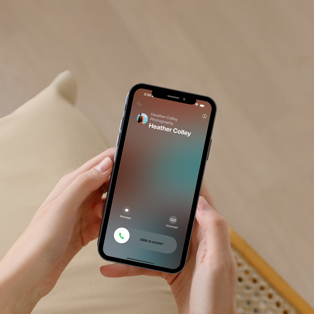 Hand holding iPhone displaying incoming call screen with minimalist interface on beige background.