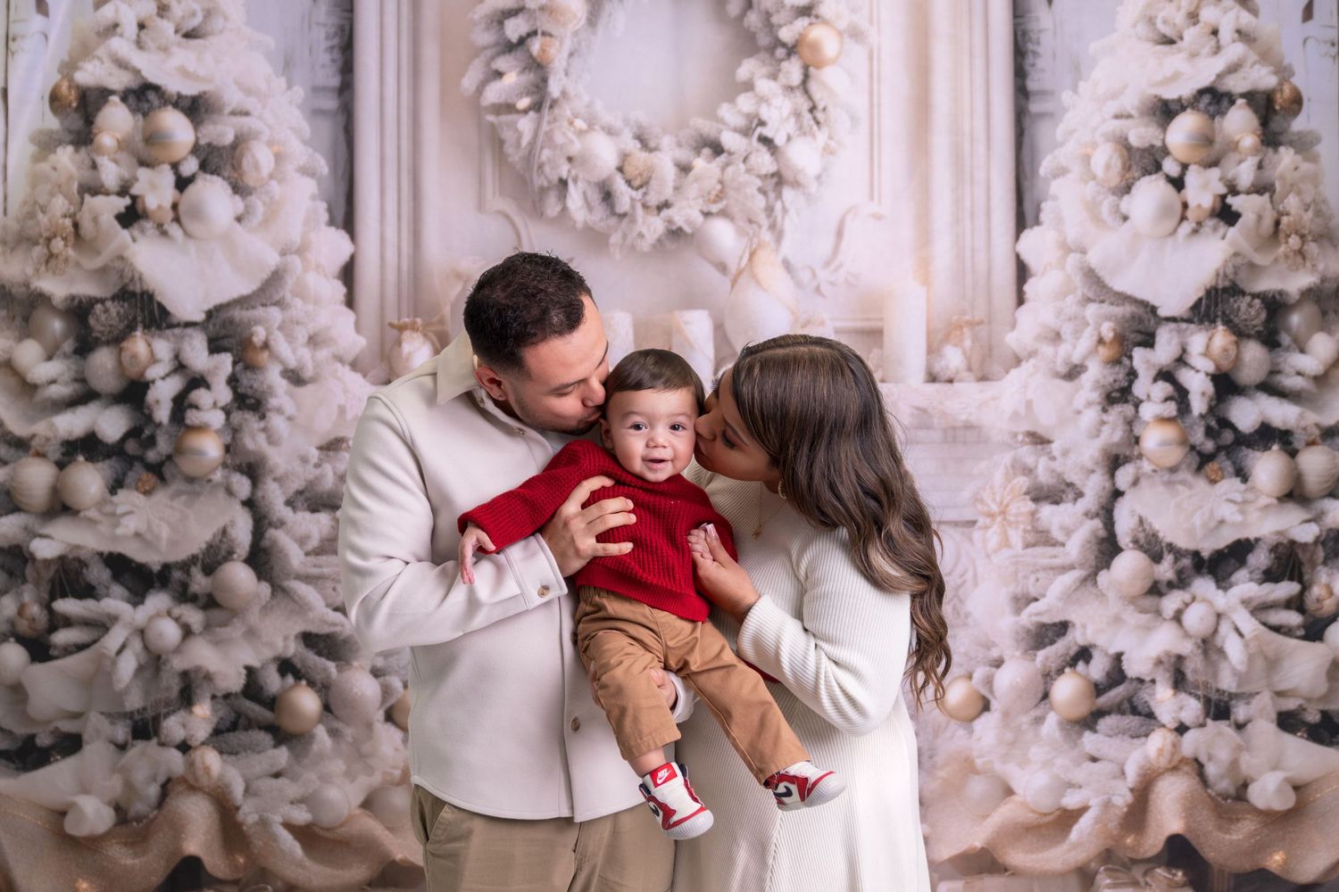 A family poses together in front of a white winter wonderland backdrop with flocked trees.