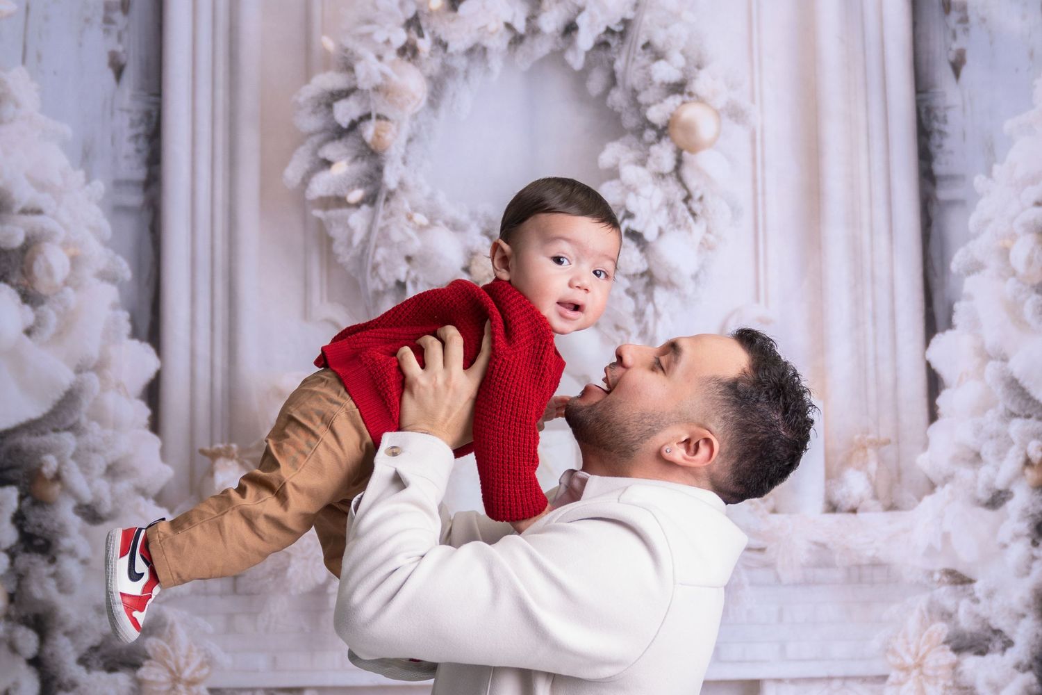 Playful family moments captured against festive white Christmas decorations and wreaths.
