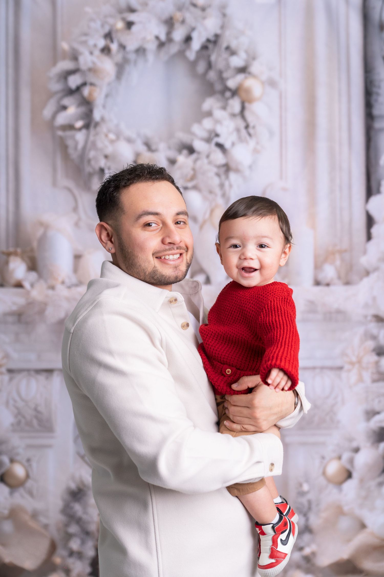 Joyful interaction between parent and child wearing red and white against holiday backdrop.