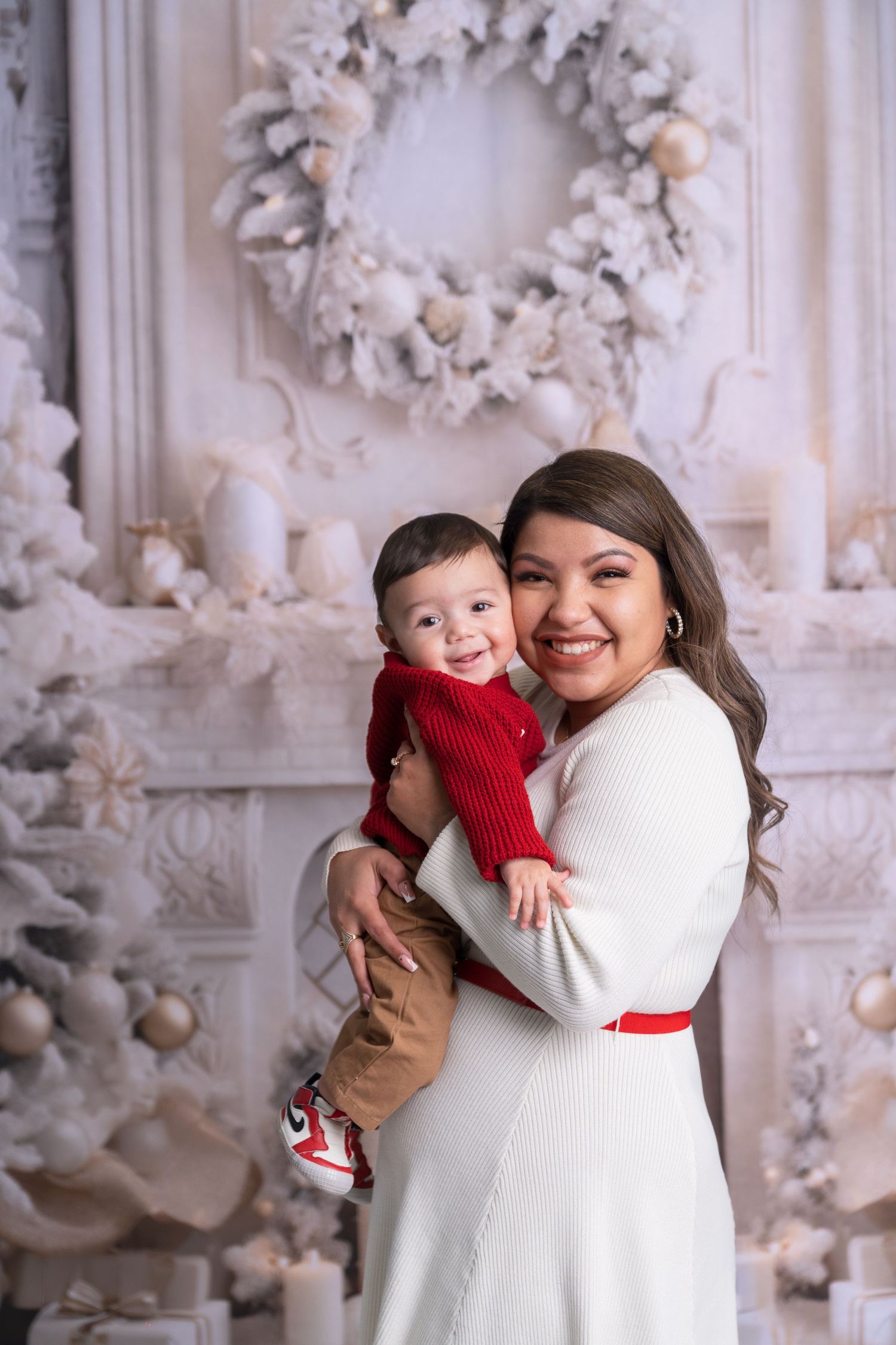 Warm family embrace captured during holiday photo session with white Christmas decor.