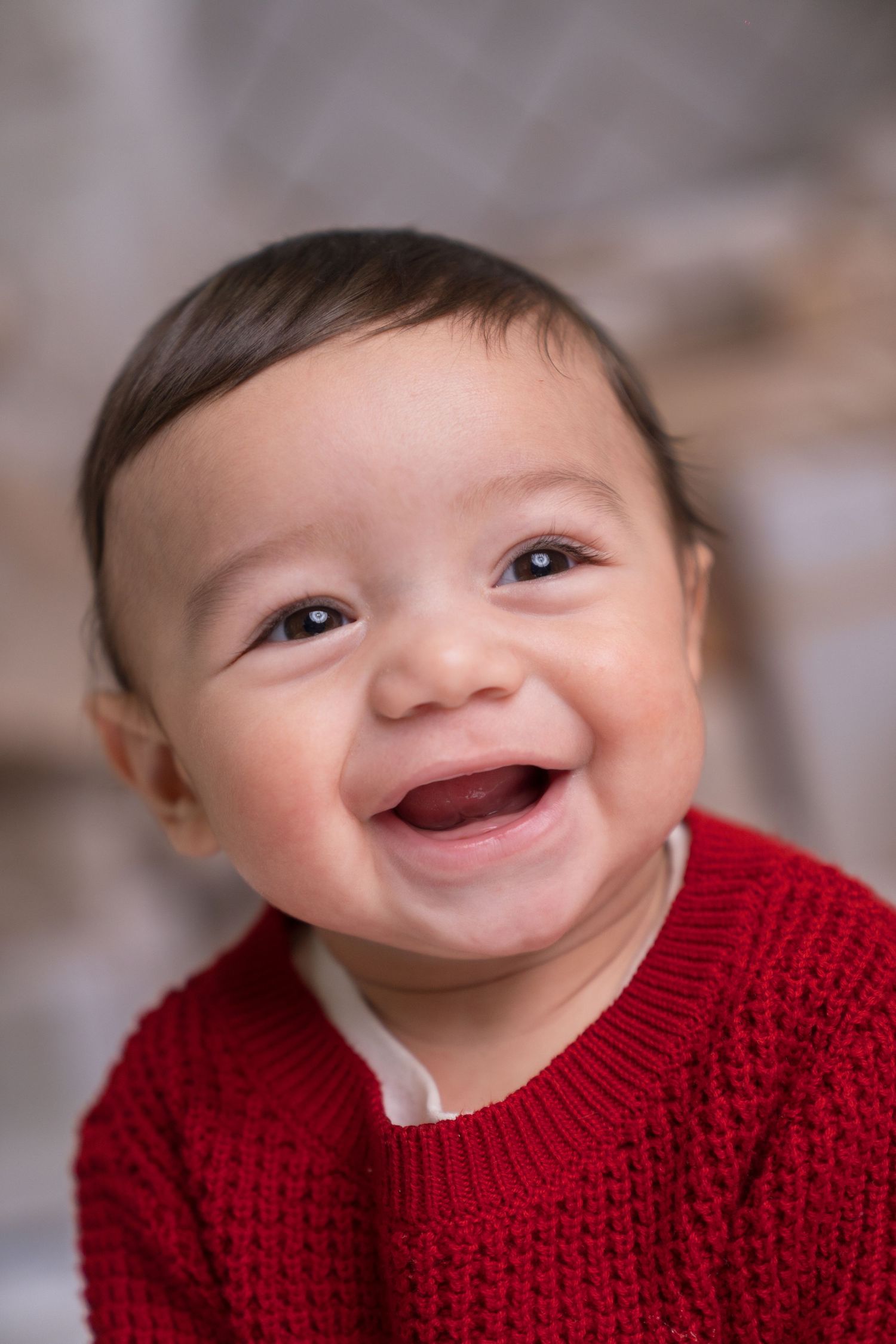 Close-up series of baby expressions showing joyful smiles while wearing red sweater.