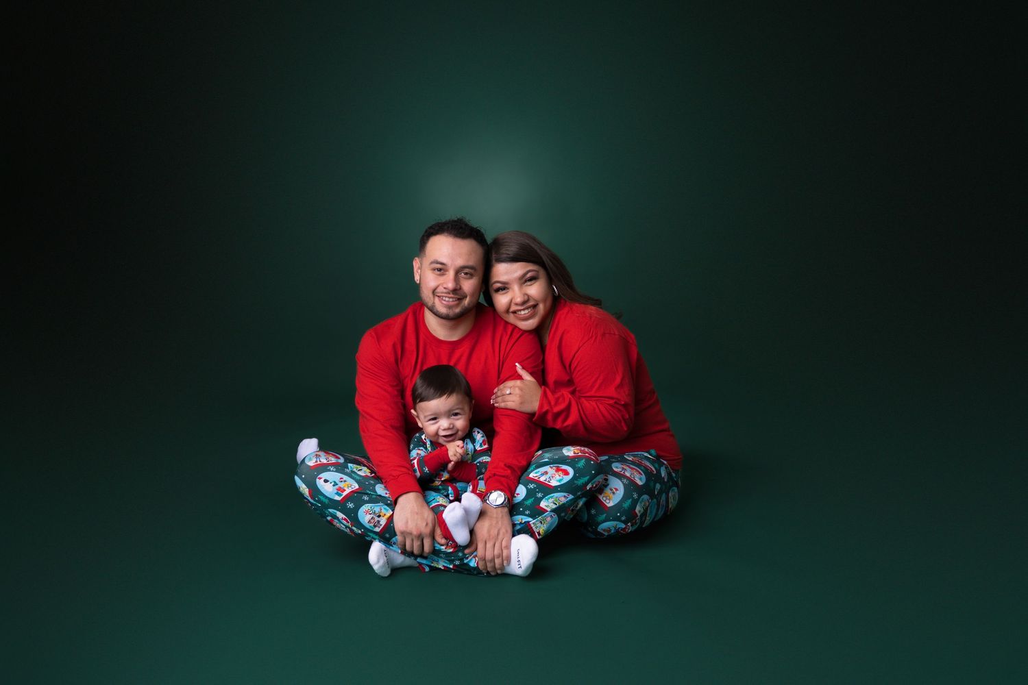 Family holiday portraits against dark green background with festive Christmas decorations.