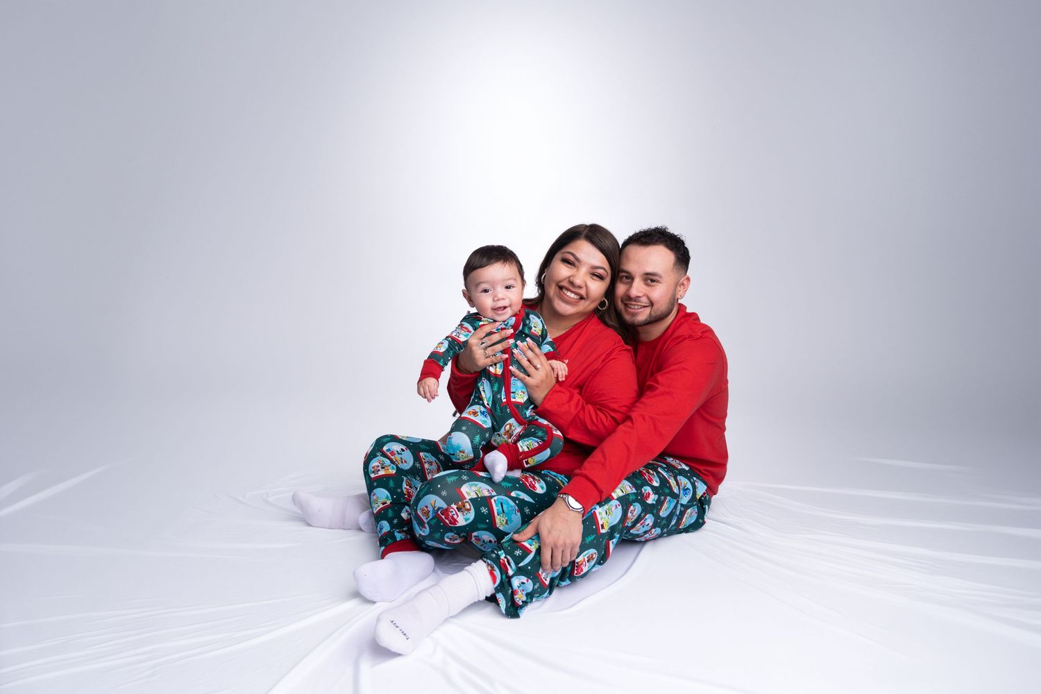 A family wearing coordinated holiday outfits poses together on a white seamless background.