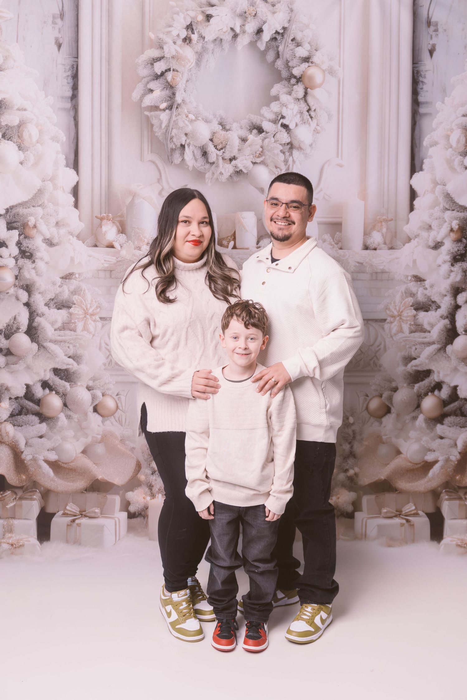 Cozy winter photo session with white decor and flocked Christmas trees in background.