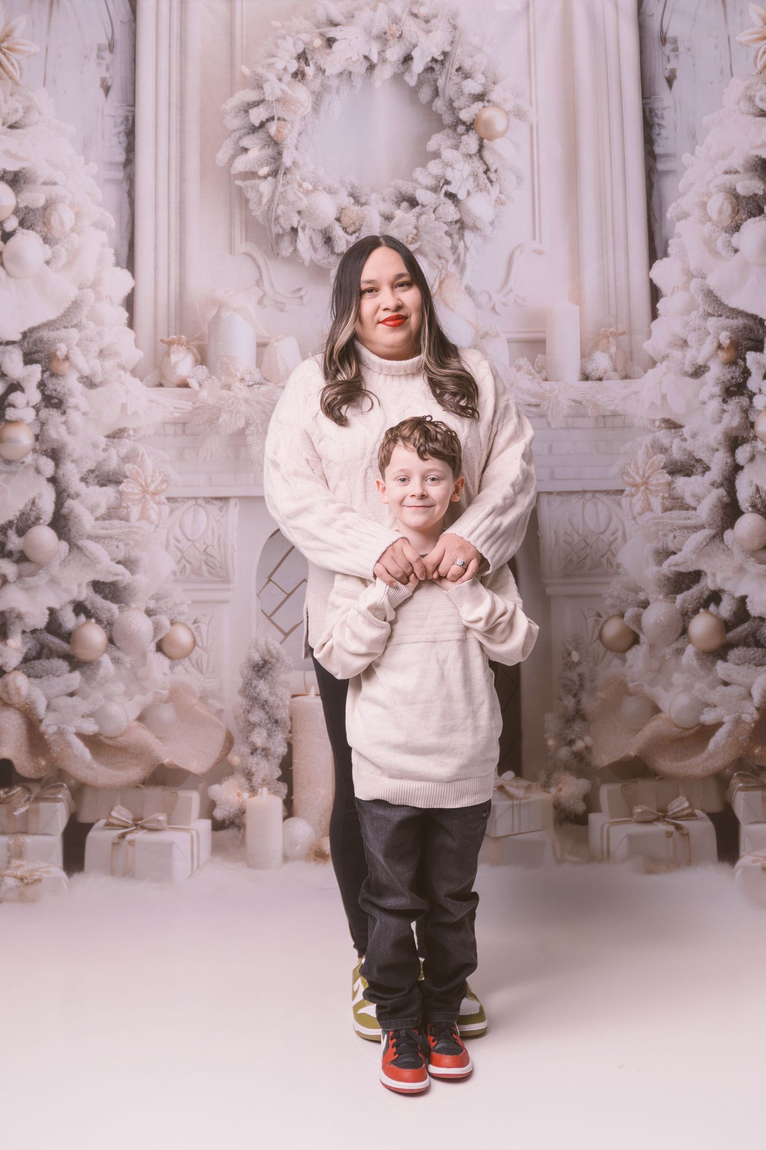 Playful family photo session with white Christmas wreaths and decorative backdrop.