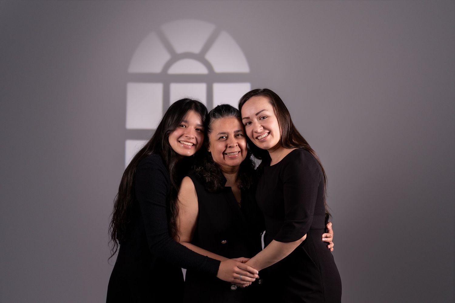 Studio photography featuring three figures in black against dramatic lighting.