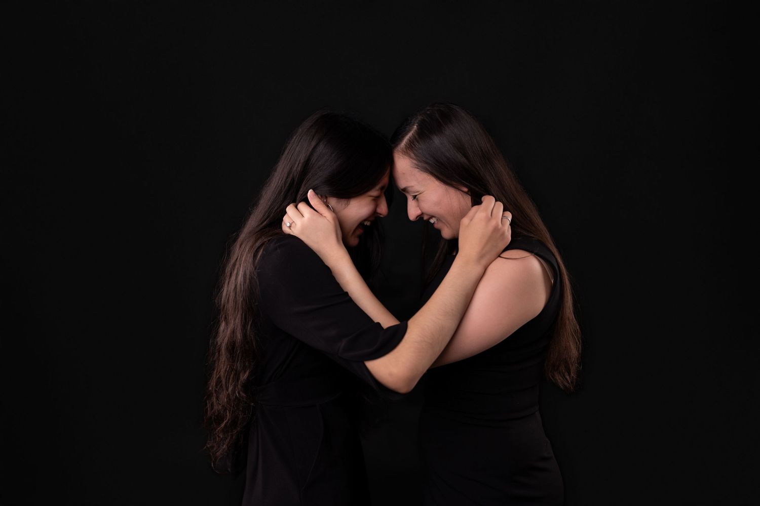 Two people in black share an intimate moment with hands on each other's faces.