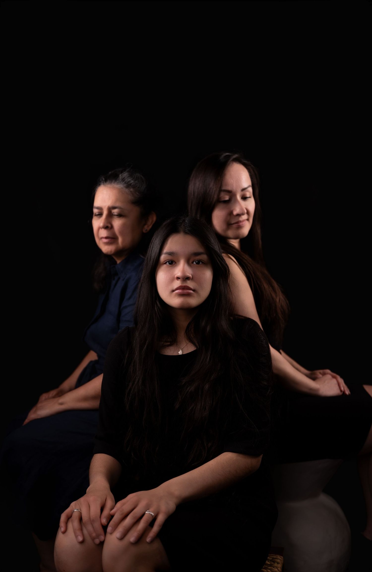 Artistic portrait of tthree people in intimate pose with dramatic shadows.