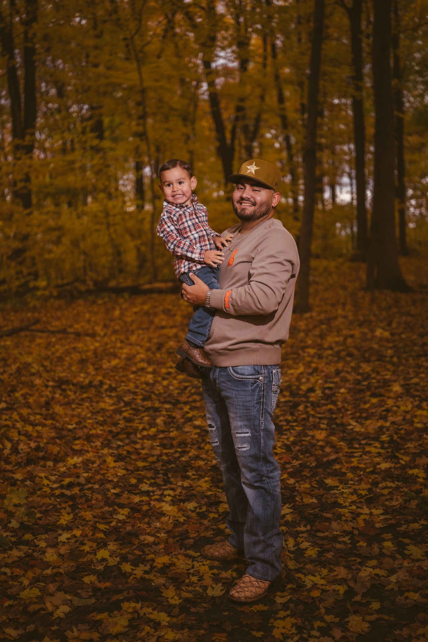 A tender moment shared in a forest covered with golden autumn leaves.