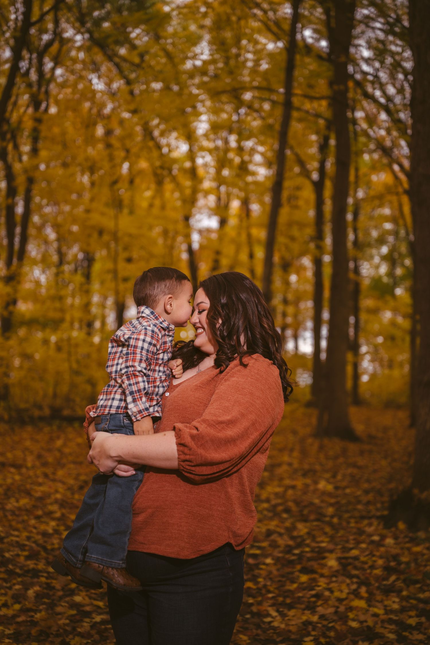 A playful autumn photoshoot in a forest filled with golden leaves and warm tones.