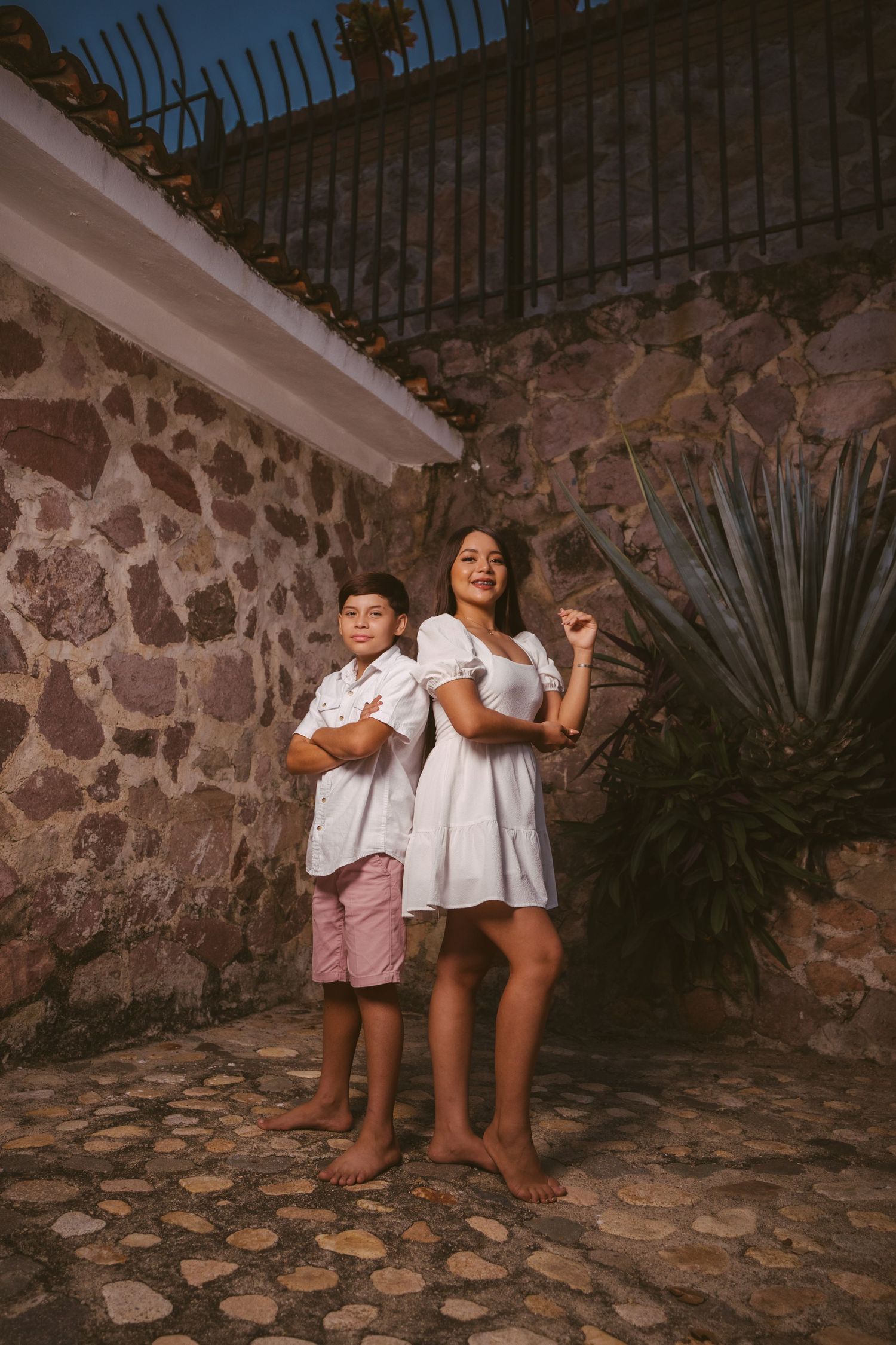 Casual family portraits against rustic stone wall with evening lighting.