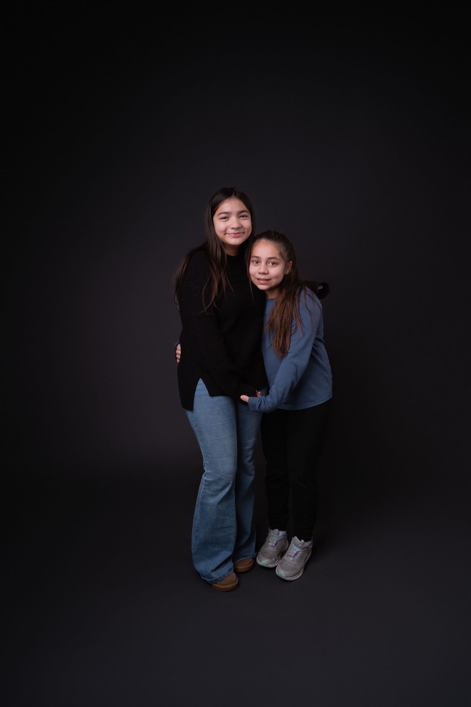 Two people in casual wear share a warm moment during studio photography session.