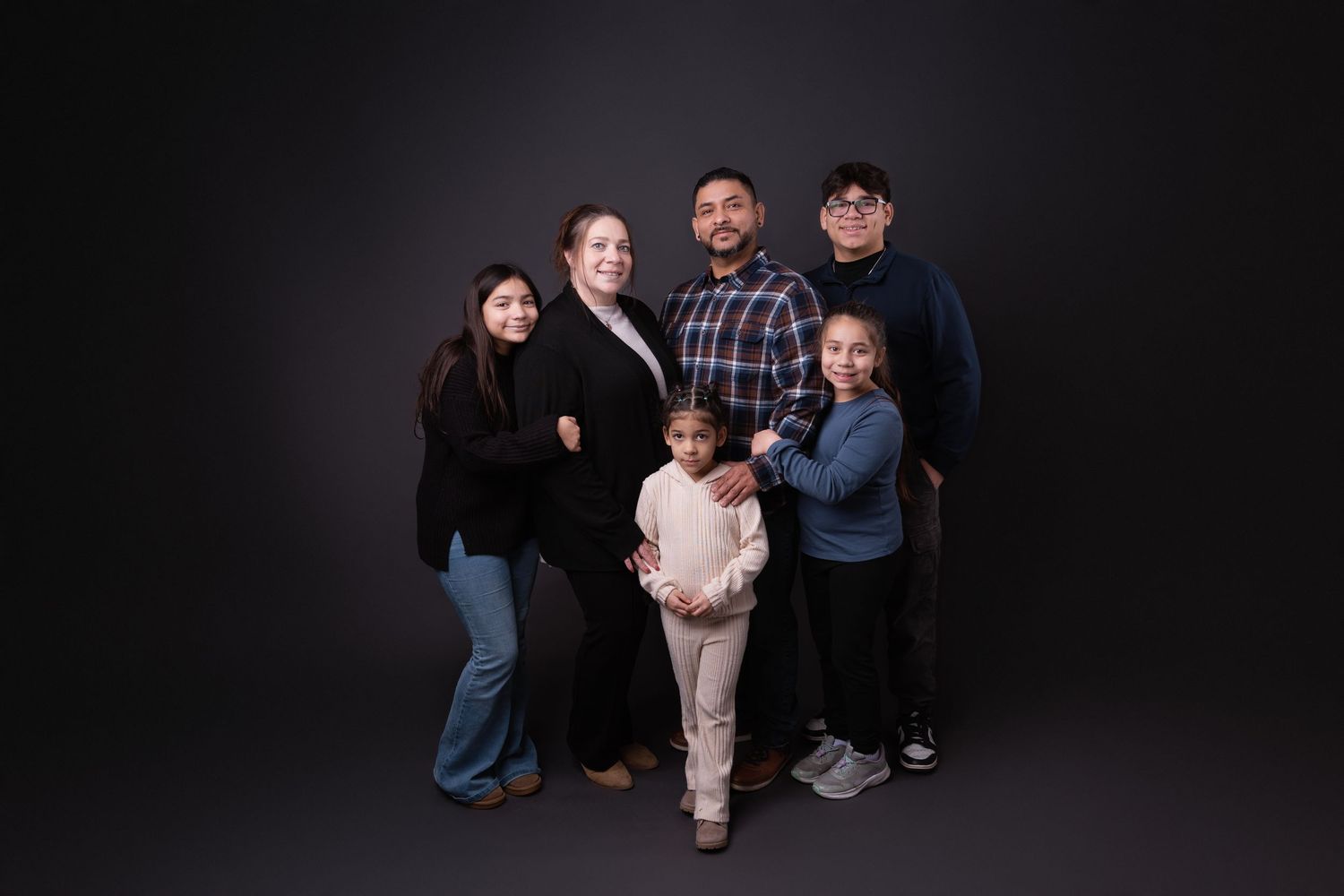 Group photo of family members posing together in studio with dark background.