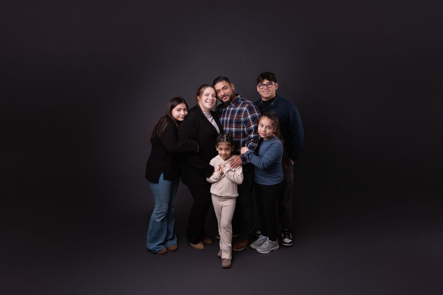 A family poses in front of a modern house exterior at dusk.