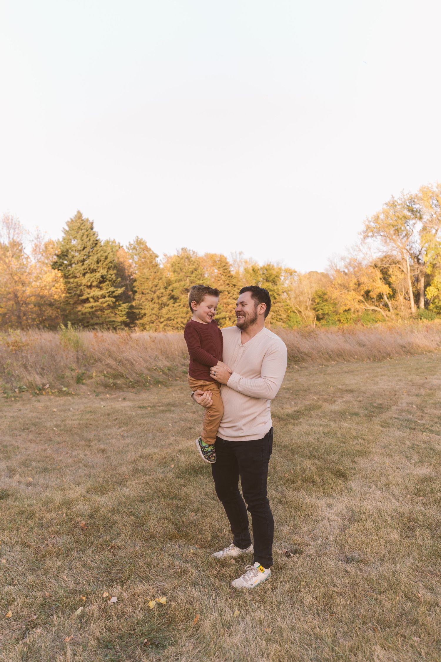 Parent and child sharing tender moment in autumn field at sunset.