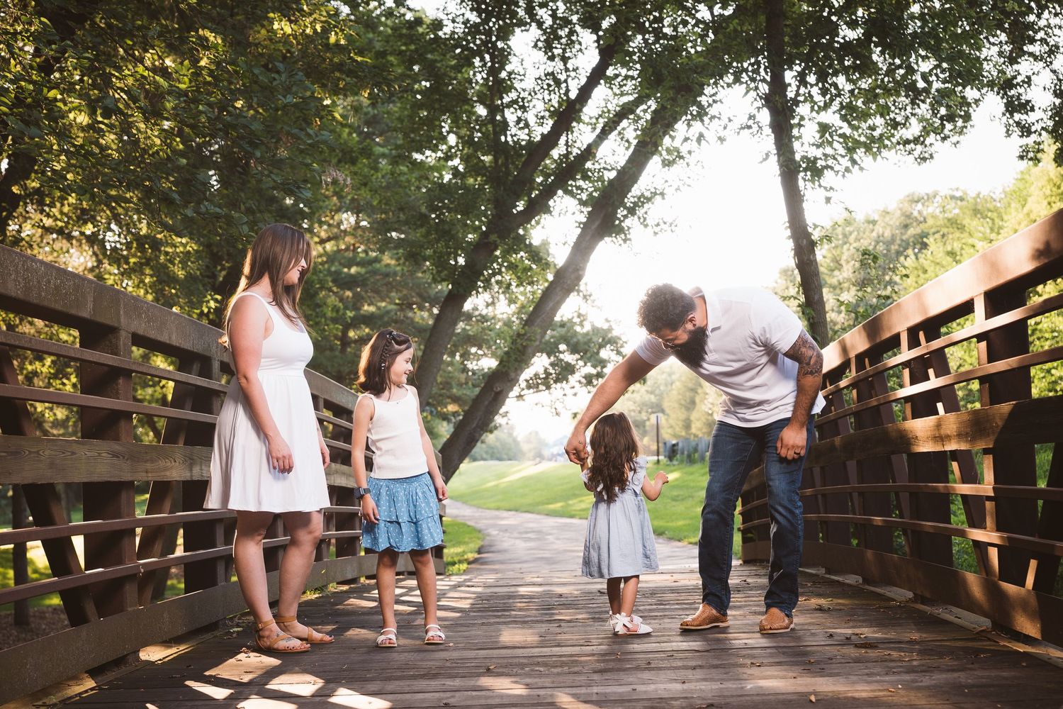 Multiple groups enjoying a peaceful walk on a tree-lined wooden bridge pathway.