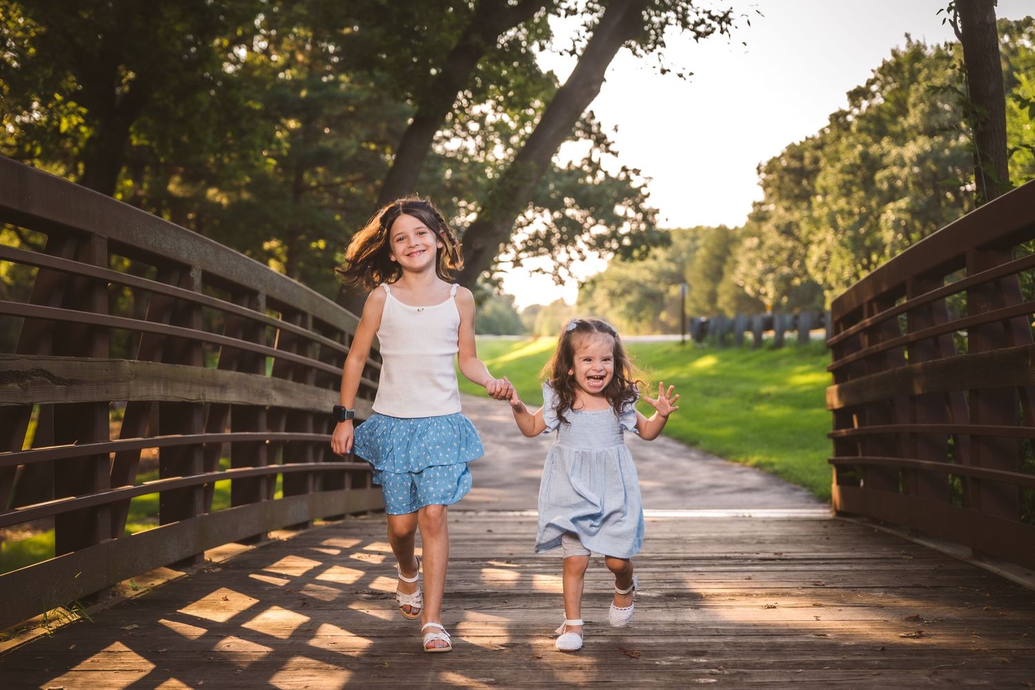 Children running and playing on a wooden bridge pathway during sunset.