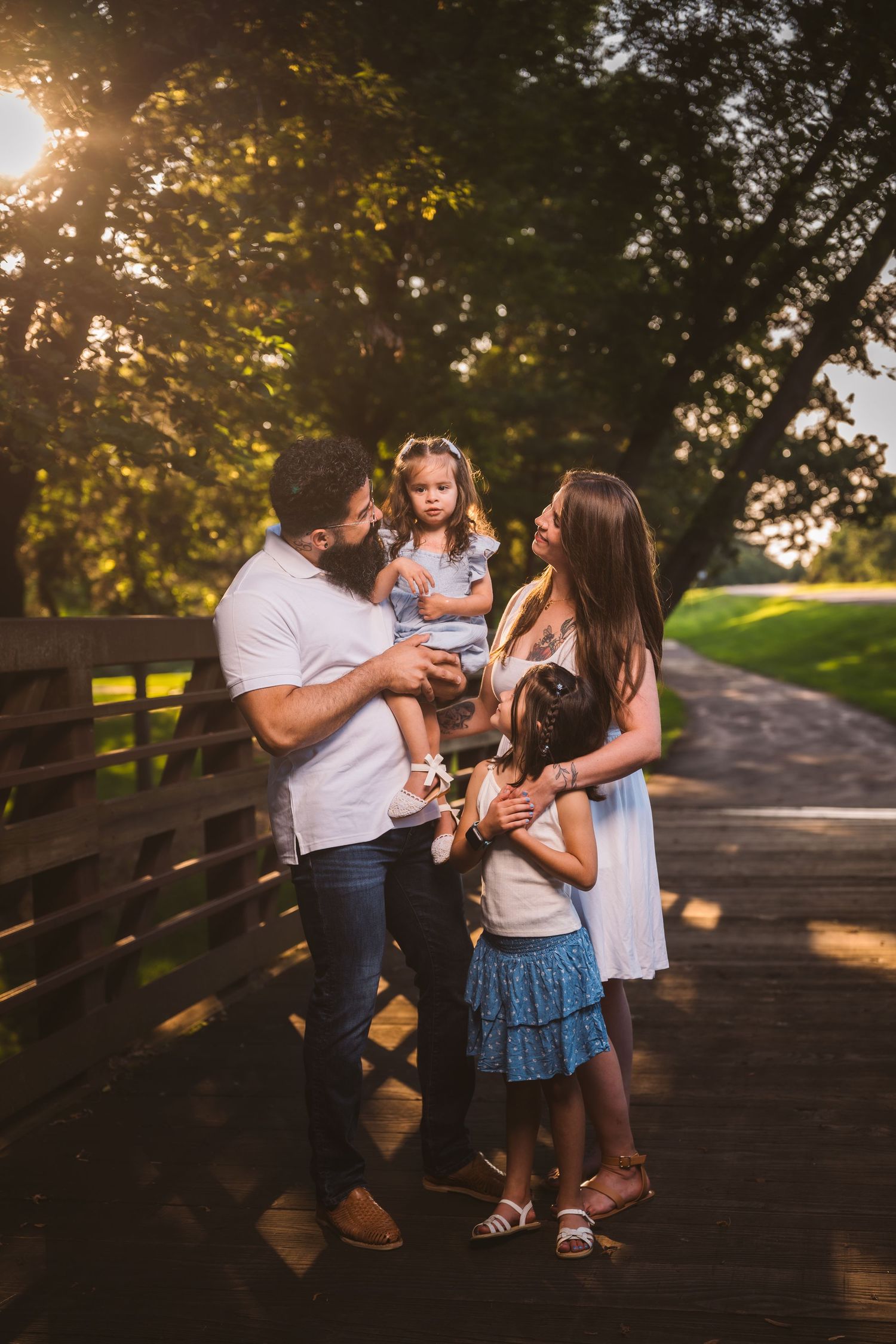 Family enjoying playful moments together on a wooden walkway at sunset.
