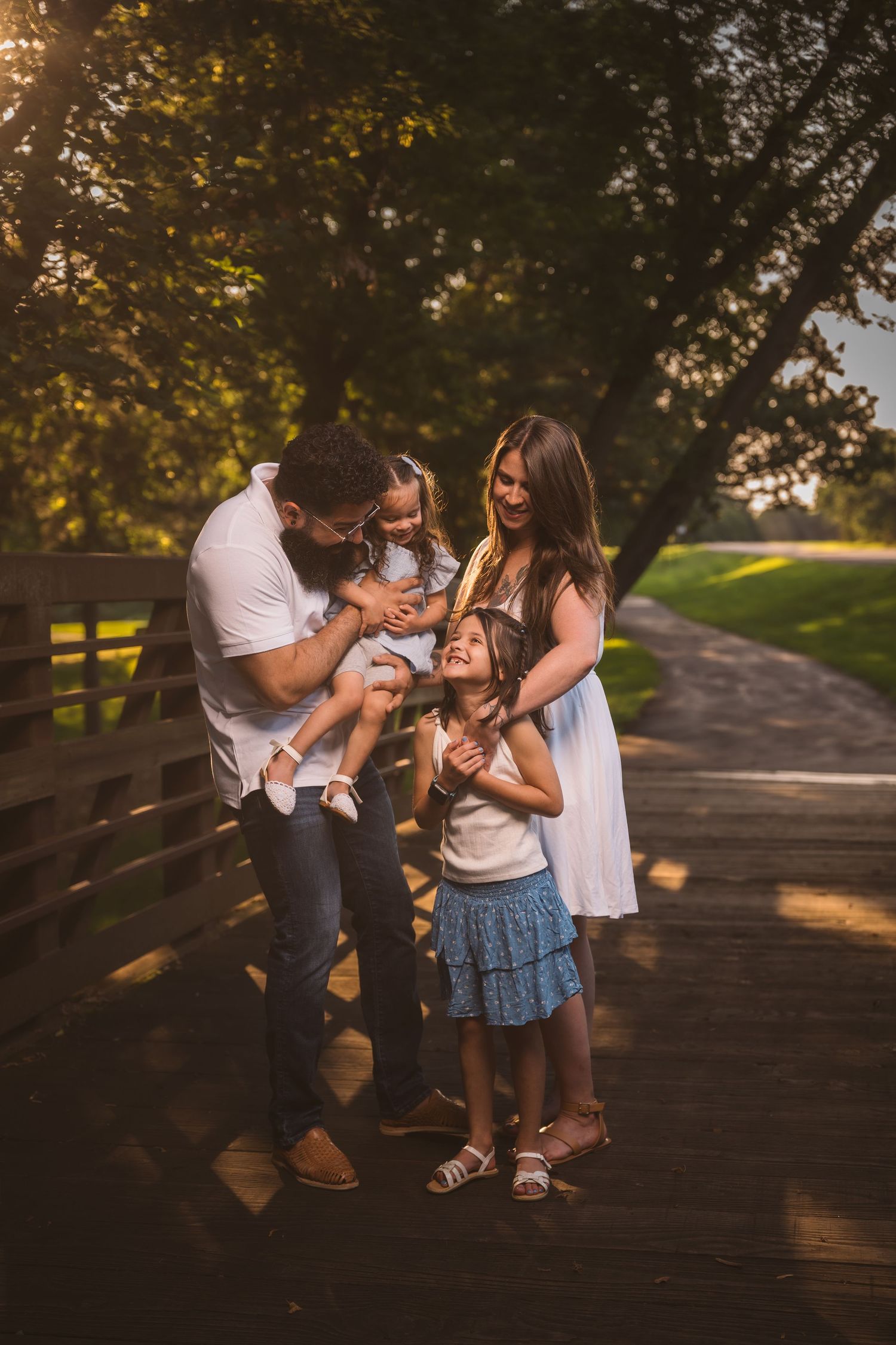 Sweet family interaction filled with laughter on an outdoor bridge path.