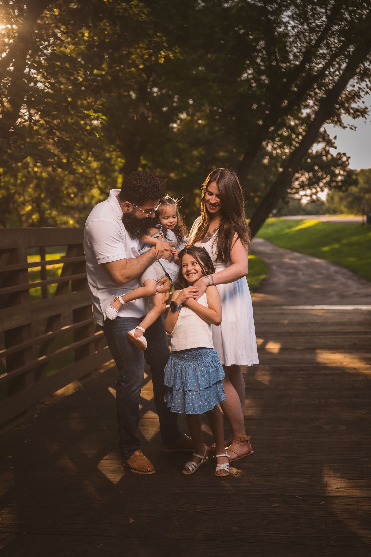 Family sharing tender moments together on a wooden bridge path.