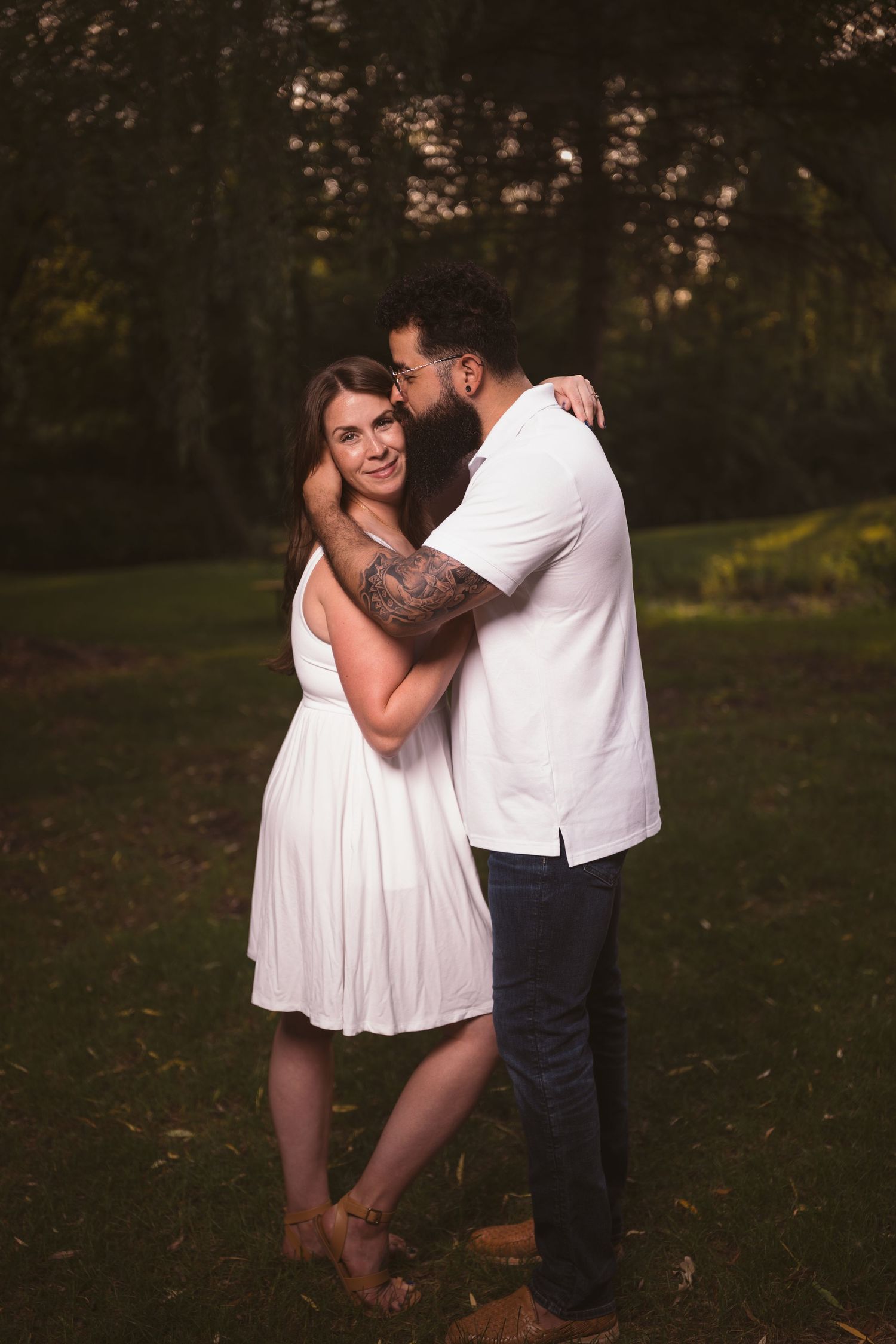 A couple in white and dark clothing sharing intimate moments in a park setting.