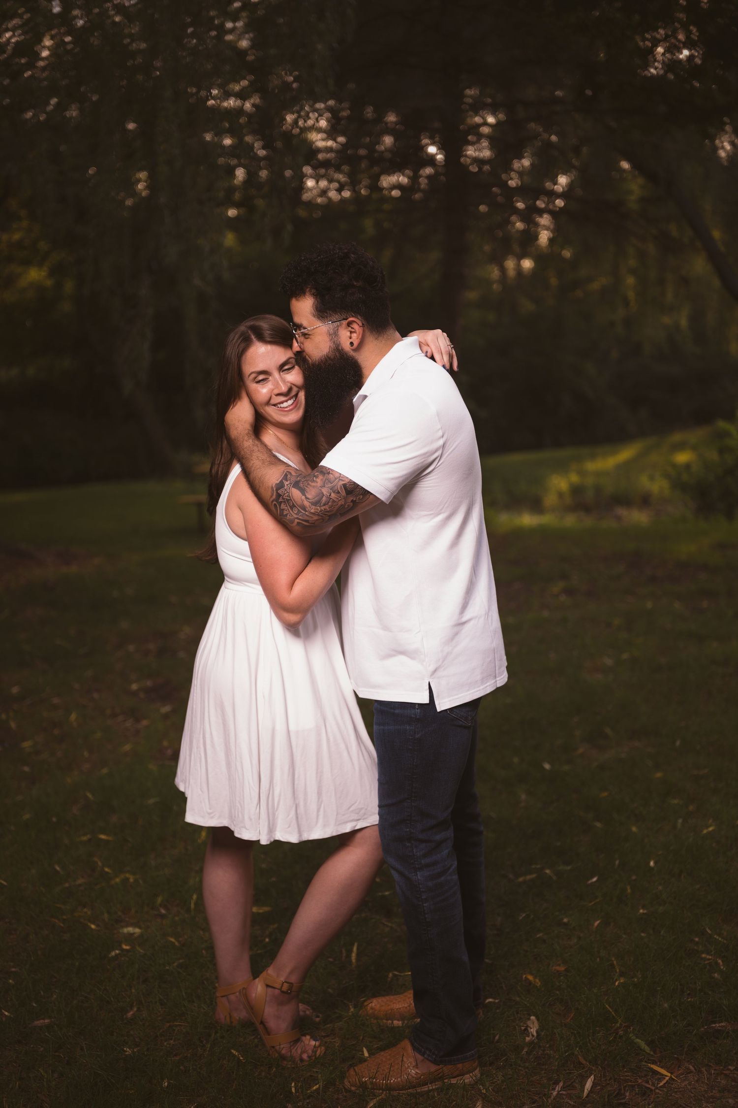 A couple sharing playful moments together in a park during golden hour.