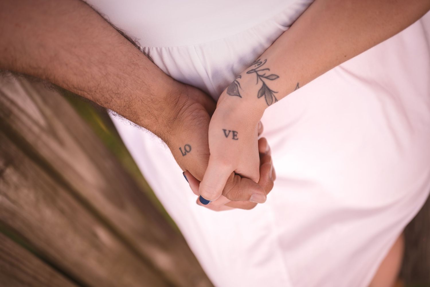 Close-up details of hands and white clothing in an intimate photoshoot.