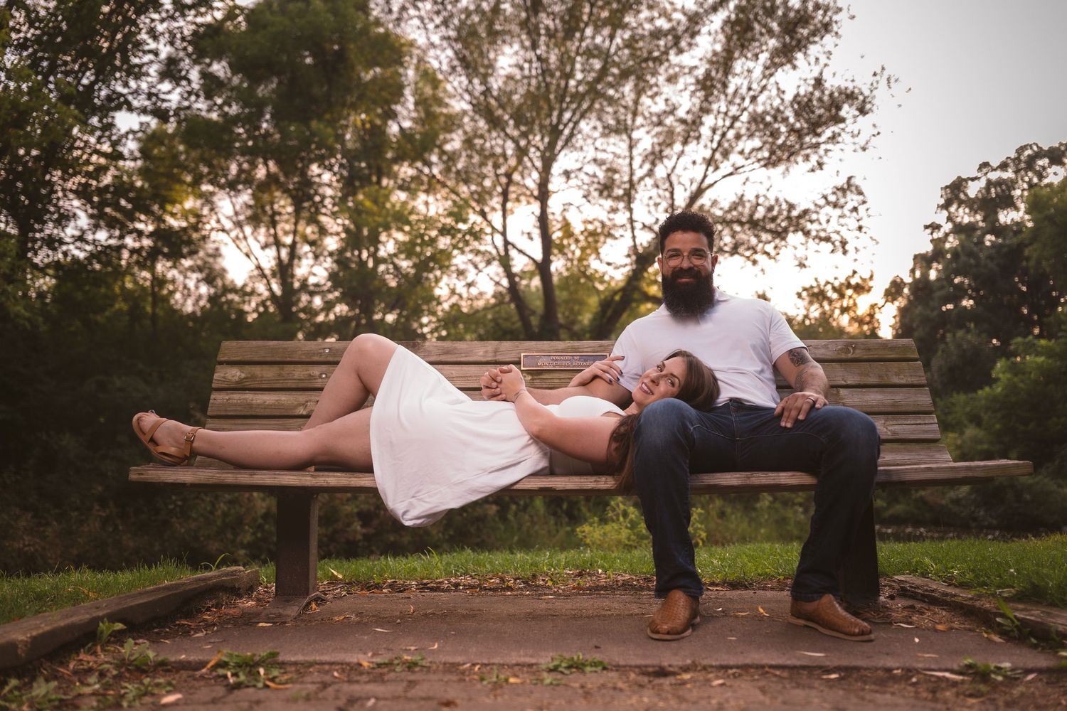 A couple relaxing together on a wooden bench in a natural outdoor setting.