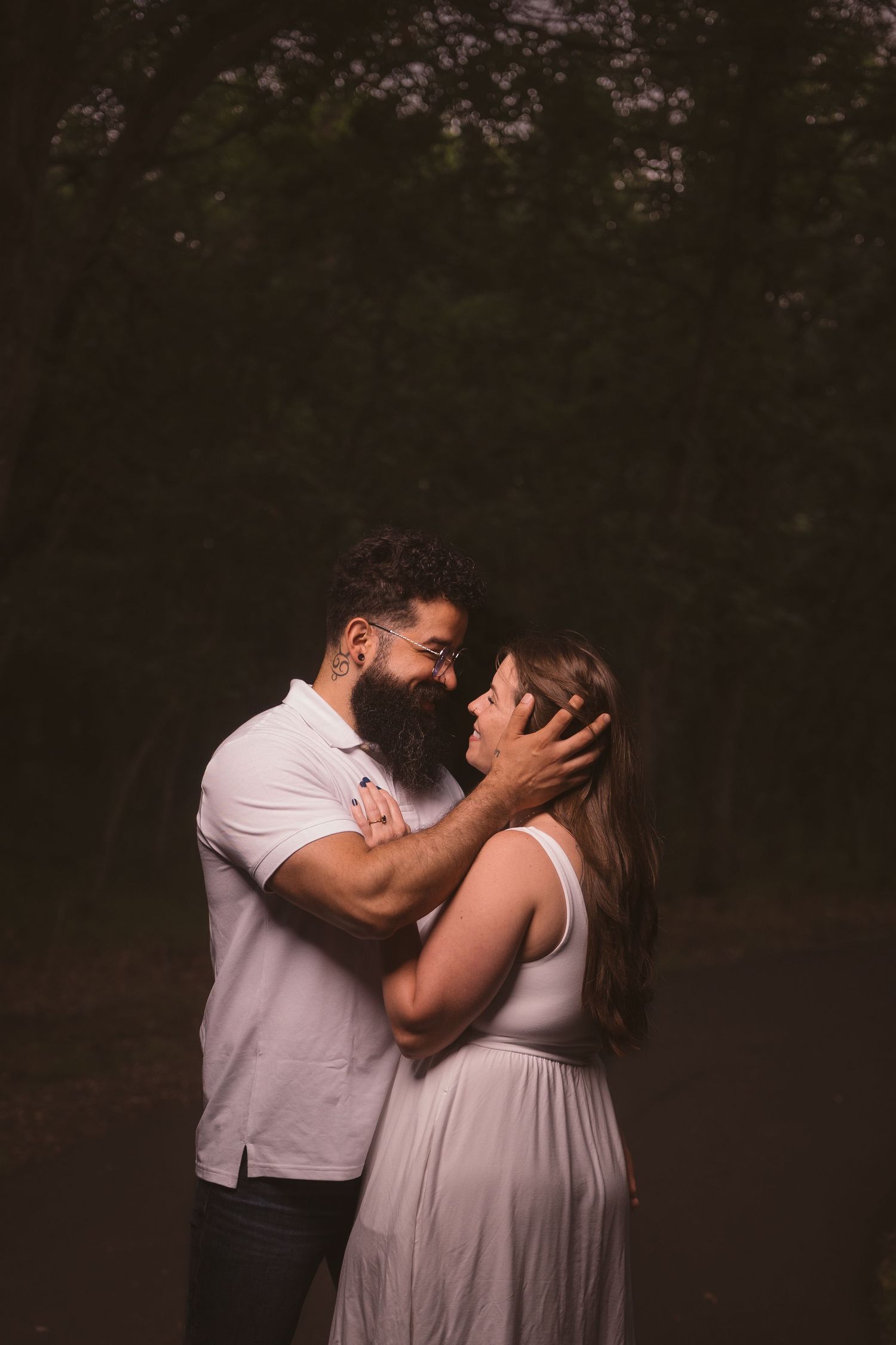 An intimate couple's portrait session captured in dramatic lighting outdoors.