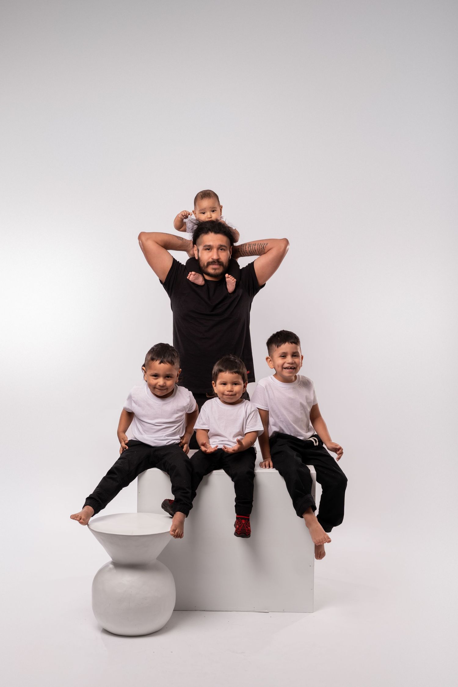 Family members strike playful poses on minimalist white studio set.