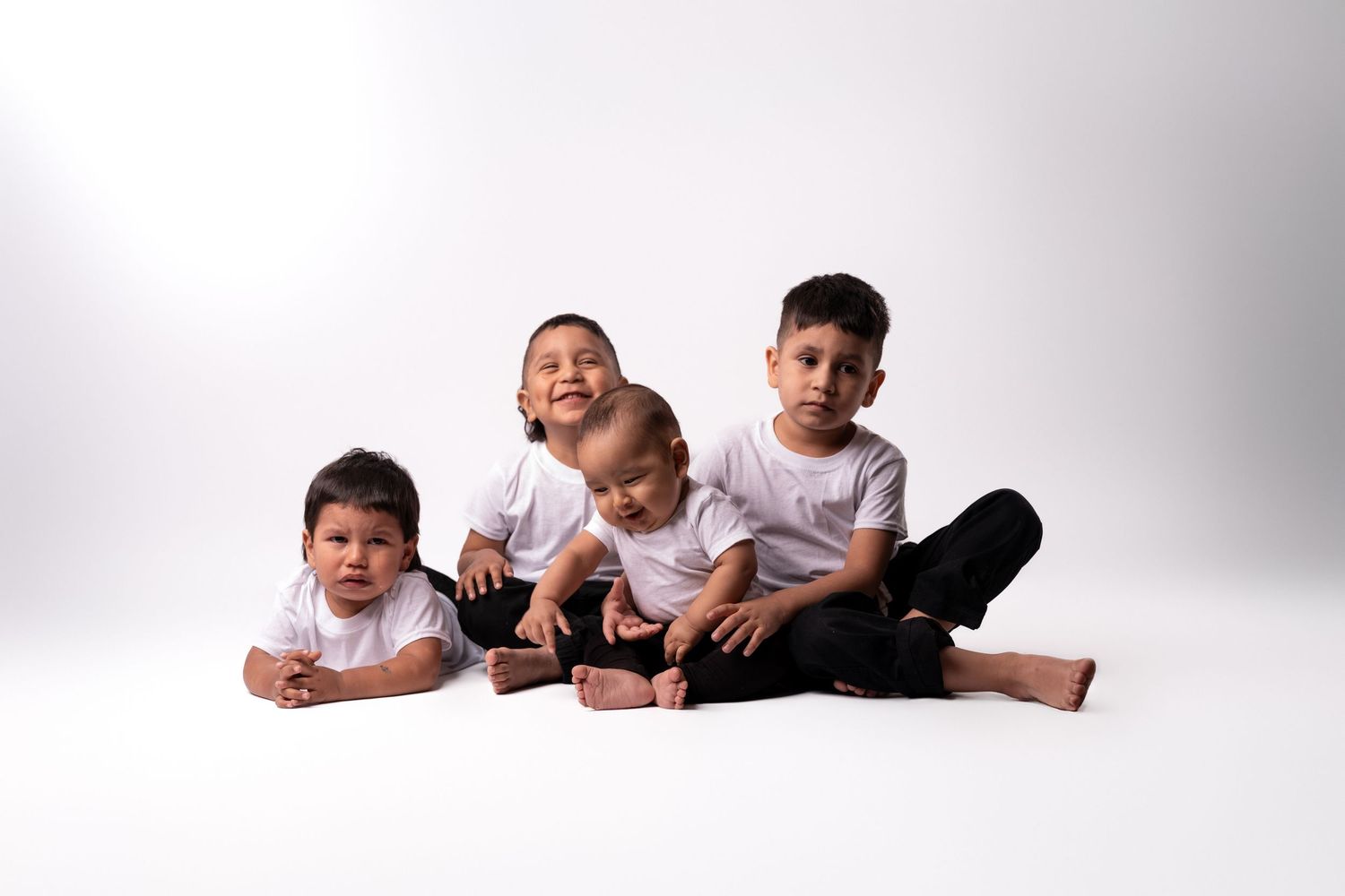 Family lying down together in row on white studio background.