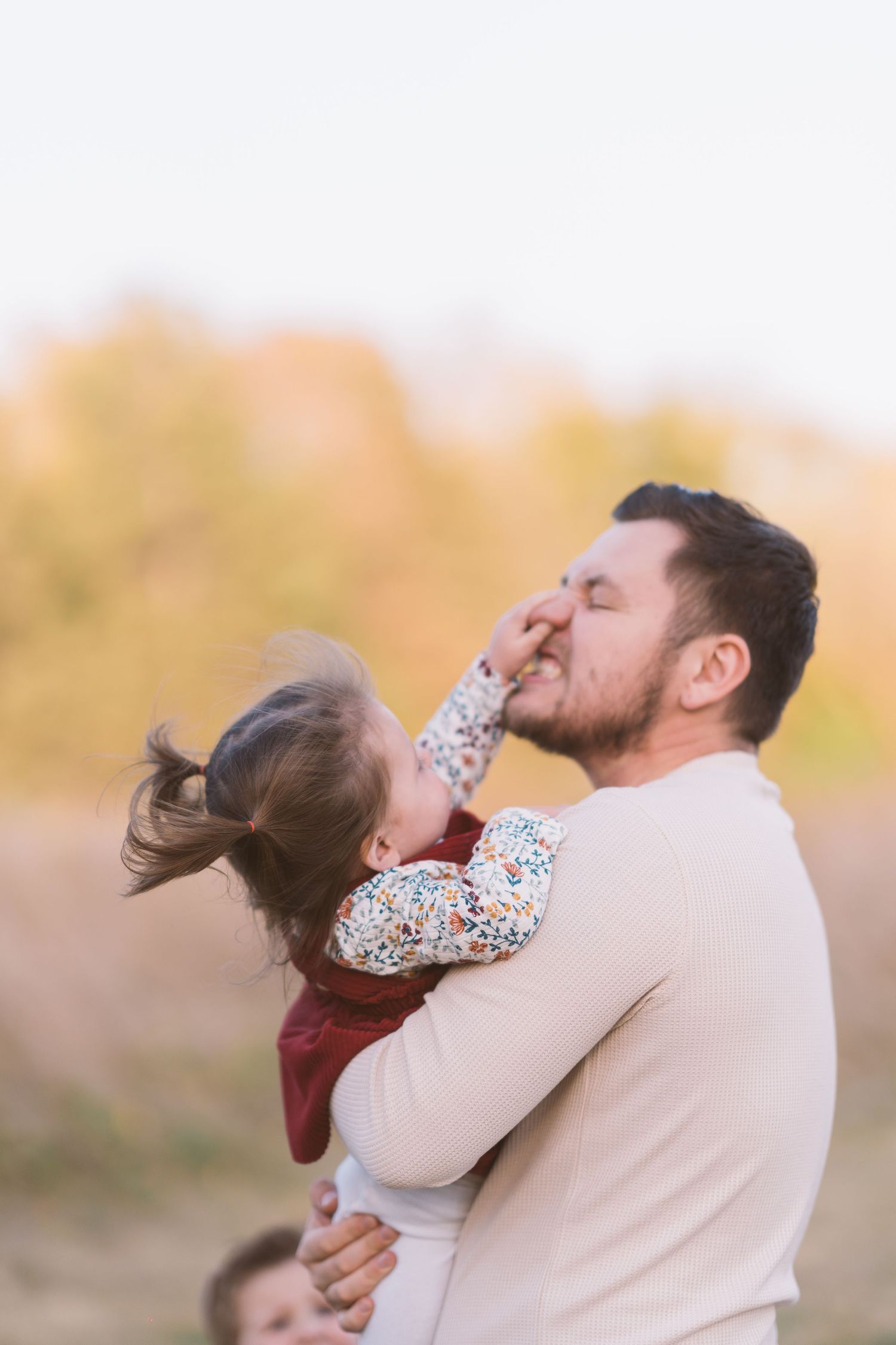 Intimate parent-child moment captured during sunset outdoor photoshoot.