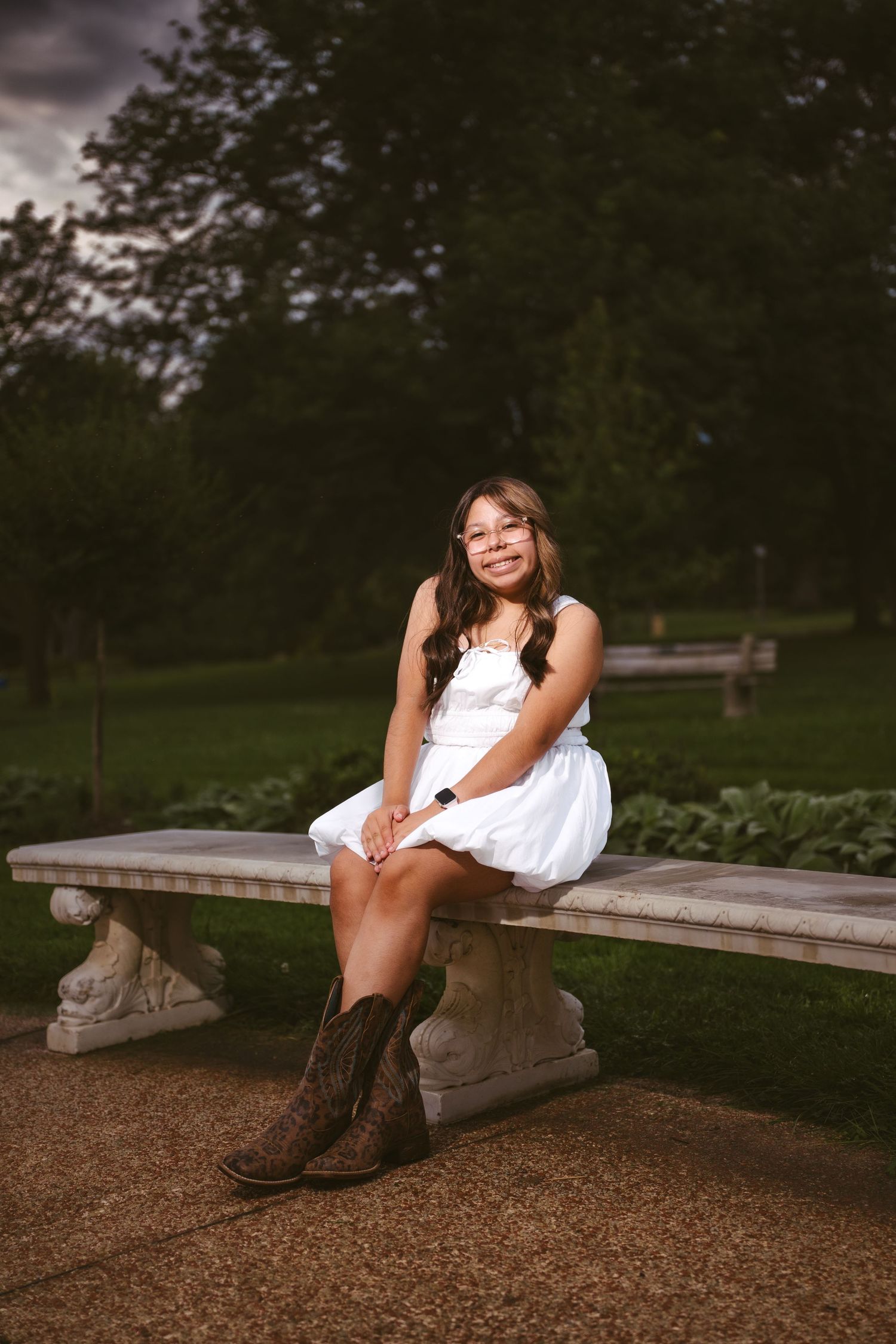 A casual portrait session on a stone bench surrounded by lush greenery at dusk.
