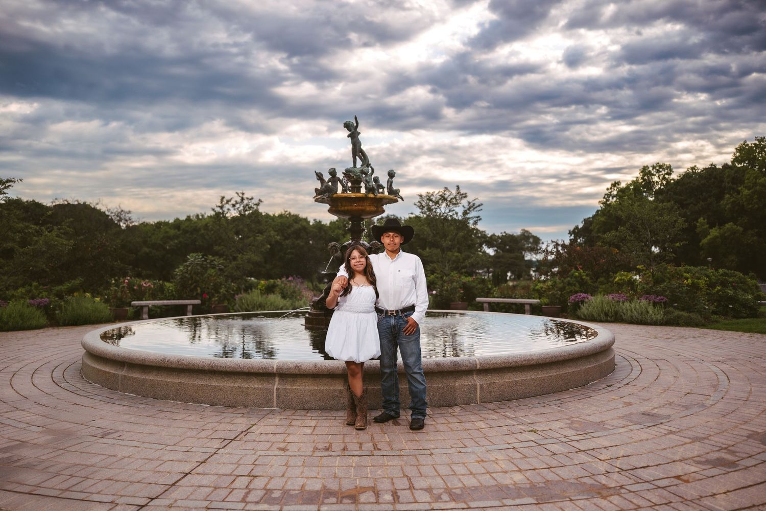 Panoramic view of a curved stone terrace with decorative fountain against moody evening clouds.