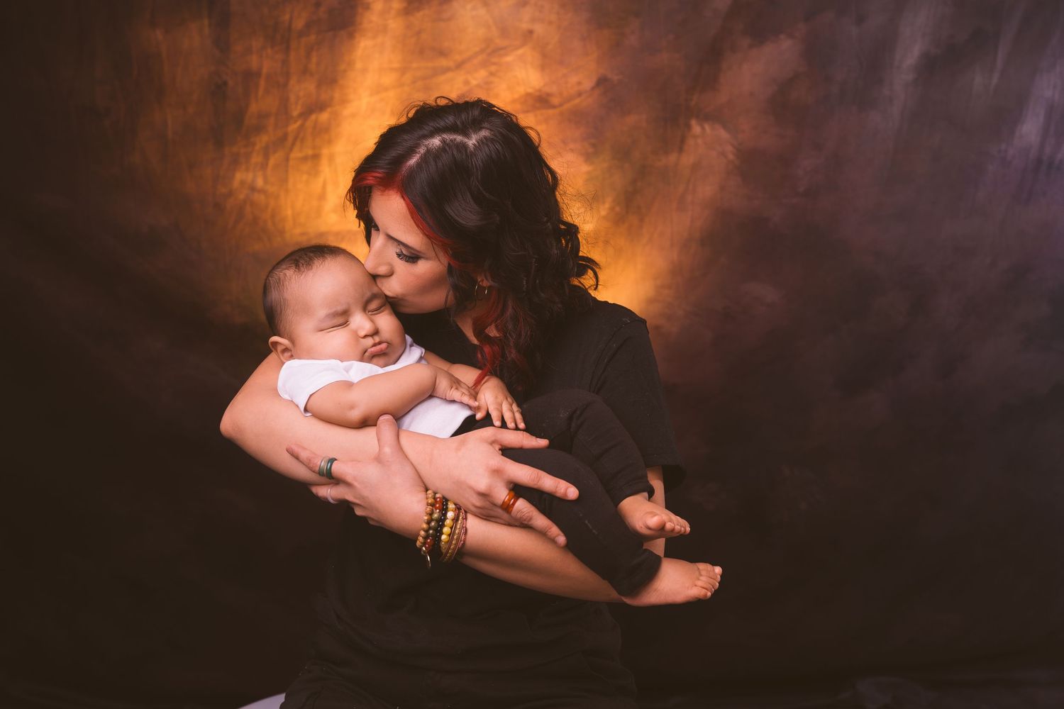 Intimate family moment captured against warm-toned studio background.